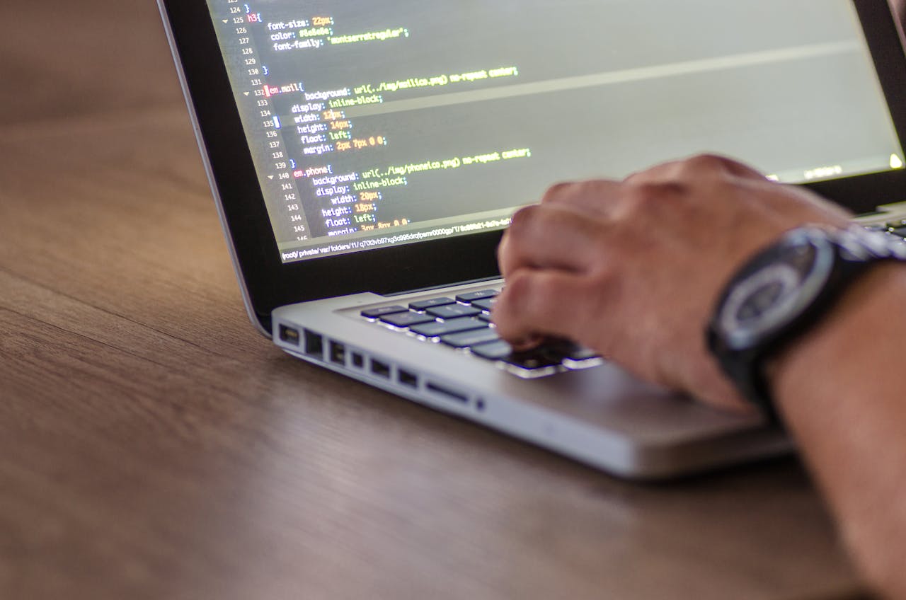 our-experience A close-up shot of a person coding on a laptop, focusing on the hands and screen.